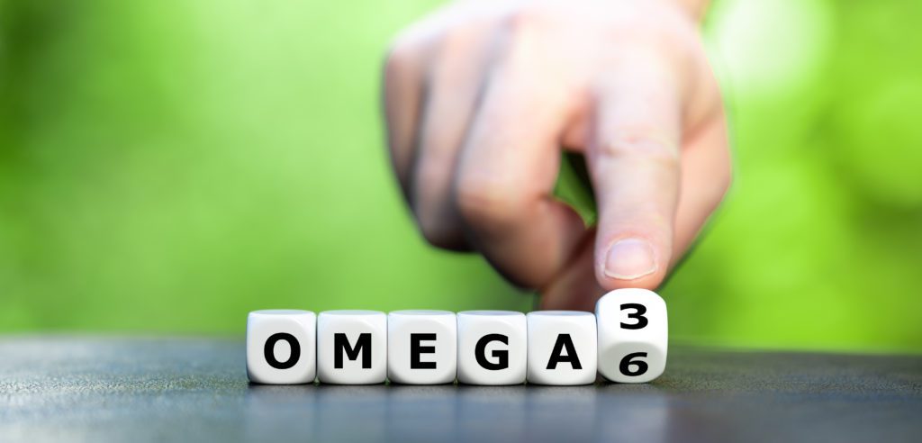 Hand turns dice and changes the expression "Omega 6" to "Omega 3"